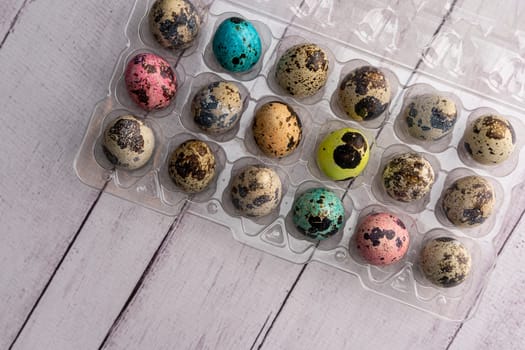colorful Easter eggs in a container on a light background. Easter greeting card. a place to copy. close-up of quail eggs. top view