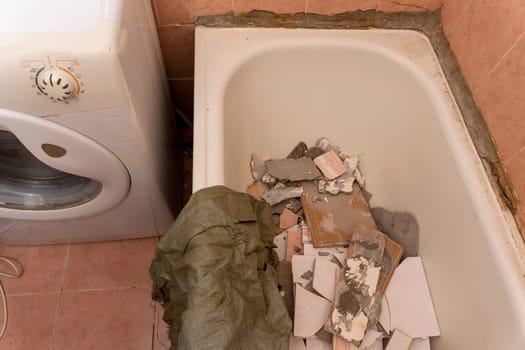 an old dirty shabby bathroom with fallen tiles. repair. A bag for construction debris.washing machine