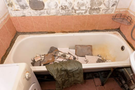 an old dirty shabby bathroom with fallen tiles. repair. A bag for construction debris.washing machine