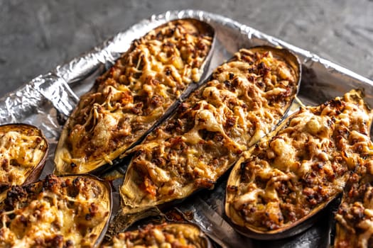 eggplant baked with meat on a baking sheet. view from above. close-up. Eggplant halves stuffed with minced meat, spices and cheese, for baking in the oven. Delicious and healthy food.