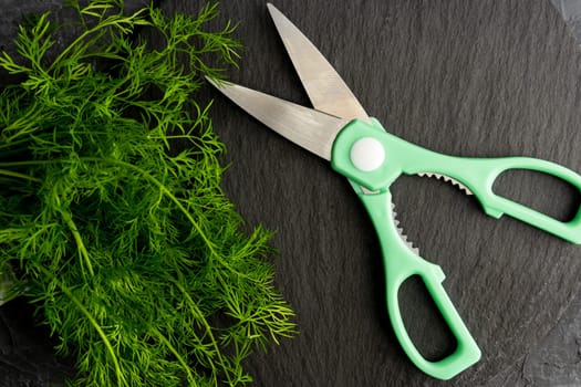 kitchen scissors cutting dill in the kitchen on a cutting board in the kitchen. Close-up of kitchen accessories. cooking. Fresh greens. Healthy eating.