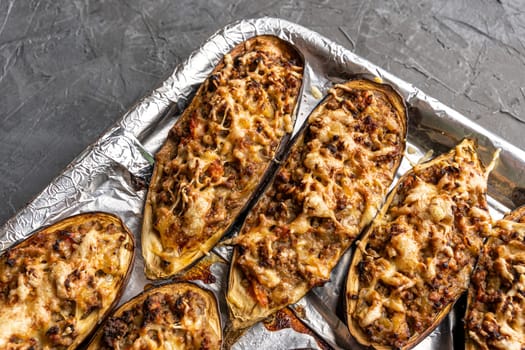 eggplant halves baked with meat on a baking sheet. view from above. Eggplant halves stuffed with minced meat, spices and cheese, for baking in the oven. Delicious and healthy food. copy space