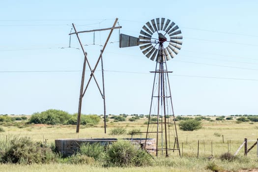 A windmill with dam and a electricity pylon between Douglas and Prieska in the Northern Cape Province