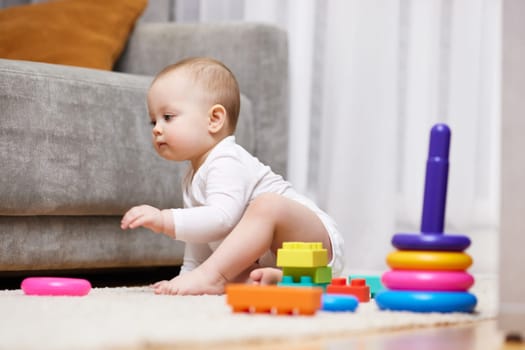 cute baby girl playing with toys on a carpet at home. Early development for kids.