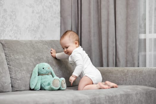 cute baby girl playing with soft toy bunny at home.