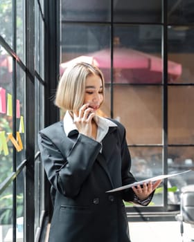 Portrait of a Happy business woman talking with a cell phone in hand holding documents.