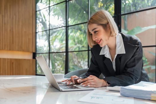 Portrait of young business woman using laptop and documents on the table at office.