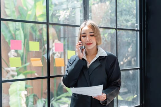 Portrait of a Happy business woman talking with a cell phone in hand holding documents.