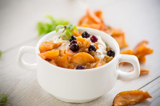 oatmeal with candied fruits, raisins in a plate on a wooden table.