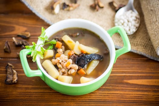 mushroom hot soup with beans in a bowl, on a rustic burlap tablecloth.