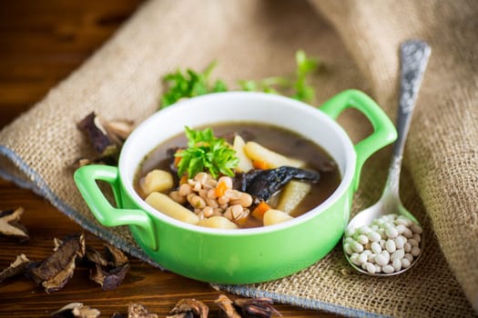 mushroom hot soup with beans in a bowl, on a rustic burlap tablecloth.