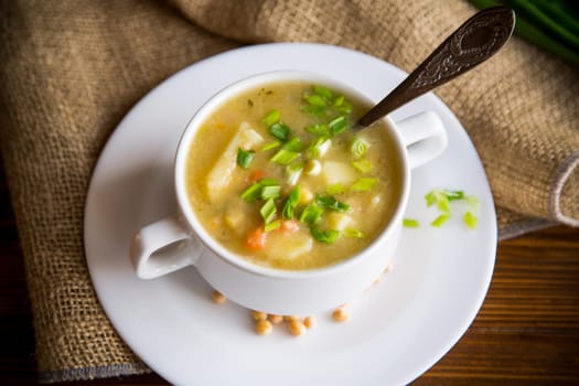 dried pea soup in a plate with herbs, on a wooden table.