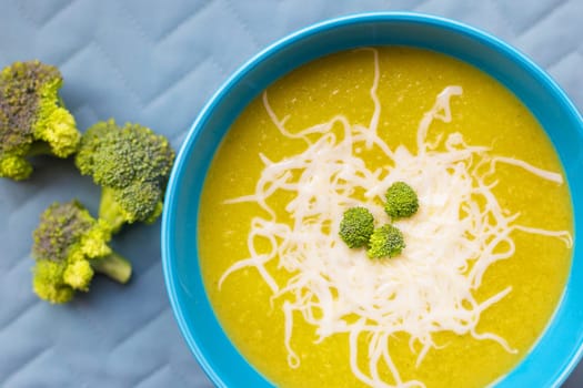 Cream of broccoli soup in the blue plate on a green napkin