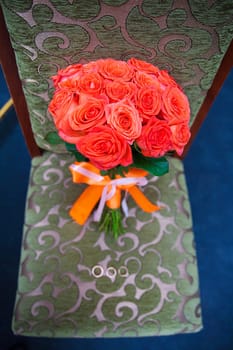 wedding bouquet with red flowers on a chair with a ring.