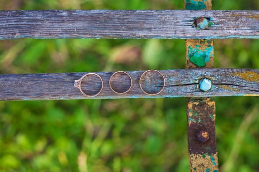 Three wedding rings on a wooden floor.