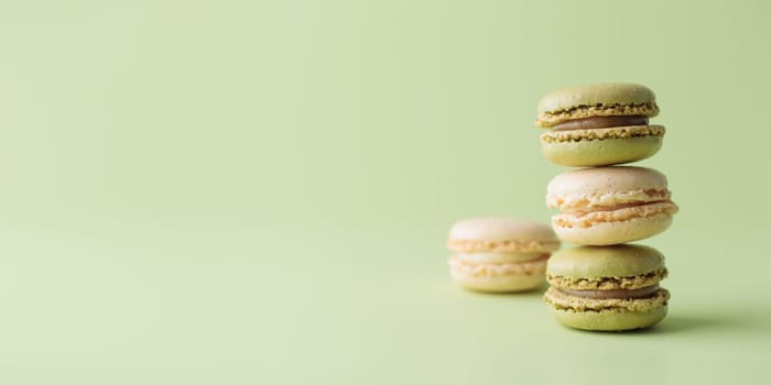 Vanilla and pistacio pastel colored eco handmade macaroons on green background. Gift for 8 March, International Women's Day, Valentine Day. Horizontal banner with copyspace