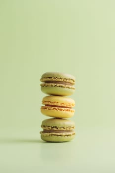 Lemon and pistacio pastel colored eco handmade macaroons on green background. Gift for 8 March, International Women's Day, Valentine Day. Vertical banner with copyspace