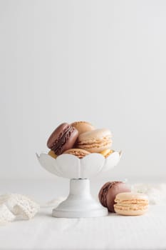 Chocolate, vanilla, coffee eco handmade natural macaroons in a vase on white table. Gift for 8 March, International Women's Day, Valentine Day. Vertical banner closeup with a copyspace