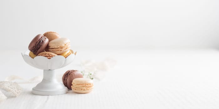 Chocolate, vanilla, coffee eco handmade natural macaroons in a vase on white table. Gift for 8 March, International Women's Day, Valentine Day. Horizontal banner closeup with a copyspace