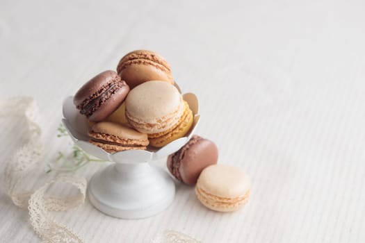 Chocolate, vanilla, coffee eco handmade natural macaroons in a vase on white table. Gift for 8 March, International Women's Day, Valentine Day. Horizontal banner closeup with a copyspace