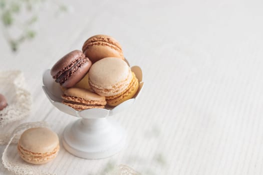 Chocolate, vanilla, coffee eco handmade natural macaroons in a vase on white table. Gift for 8 March, International Women's Day, Valentine Day. Horizontal banner closeup with a copyspace