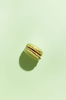 Green pistacio colored macaroon on green background. Gift for 8 March, International Women's Day, Valentine Day. Horizontal banner with copyspace