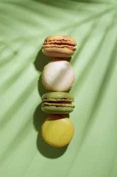 Colorful pastel eco handmade macaroons on green background with a shadow. Gift for 8 March, International Women's Day, Valentine Day. Vertical banner