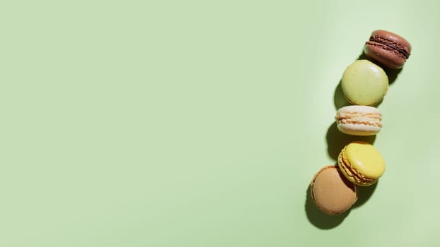 Colorful pastel eco handmade macaroons on green background with a shadow. Gift for 8 March, International Women's Day, Valentine Day. Horizontal banner with a copyspace