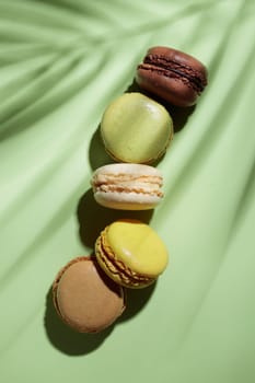 Colorful pastel eco handmade macaroons on green background with a shadow. Gift for 8 March, International Women's Day, Valentine Day. Vertical banner