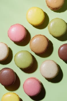 Colorful pastel eco handmade macaroons on green background with a shadow. Gift for 8 March, International Women's Day, Valentine Day. Vertical banner