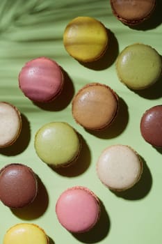 Colorful pastel eco handmade macaroons on green background with a shadow. Gift for 8 March, International Women's Day, Valentine Day. Vertical banner