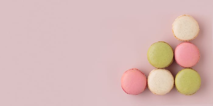 Colorful macaroons on pink background, top view, increase in profits of the confectionery production horizontal banner