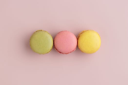 Three pastel colored macaroons on pink background, colorful french cookies pattern. Gift for 8 March, International Women's Day, Valentine Day. Horizontal banner with copyspace