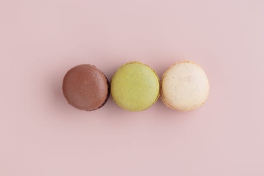 Three pastel colored macaroons on pink background, colorful french cookies pattern. Gift for 8 March, International Women's Day, Valentine Day. Horizontal banner with copyspace