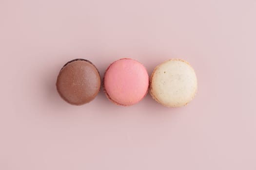Three pastel colored macaroons on pink background, colorful french cookies pattern. Gift for 8 March, International Women's Day, Valentine Day. Horizontal banner with copyspace