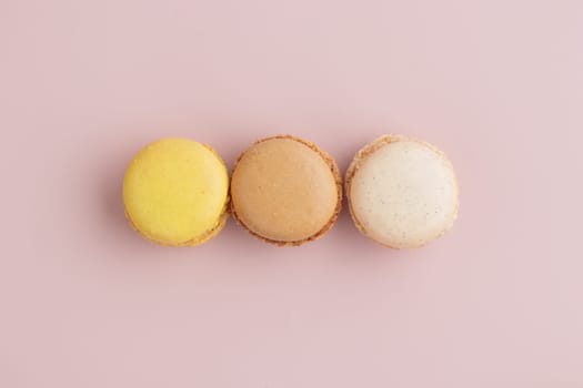 Three pastel colored macaroons on pink background, colorful french cookies pattern. Gift for 8 March, International Women's Day, Valentine Day. Horizontal banner with copyspace