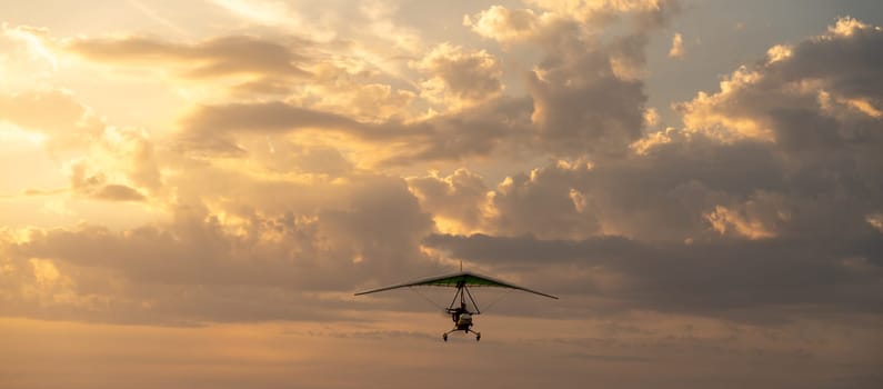 Propeller plane flies in the sunset sky. Banner, A small private hang-glider in a cloudy sky