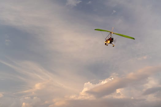 Propeller plane flies in the sunset sky. A small private hang-glider in a cloudy sky
