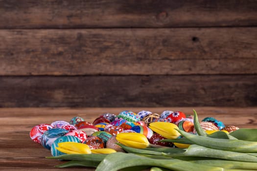 Easter composition allowing you to put your own graphic content on a free field. Yellow tulips and Easter eggs in the foreground and fuzzy boards in the background.