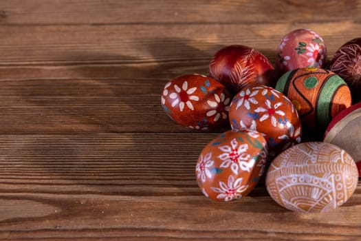 Easter composition of several Easter eggs with brown tones arranged on old brown boards. Blank bowl for adding inscriptions.