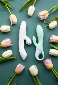 Two toys for adults lie on a green background, surrounded by tulips