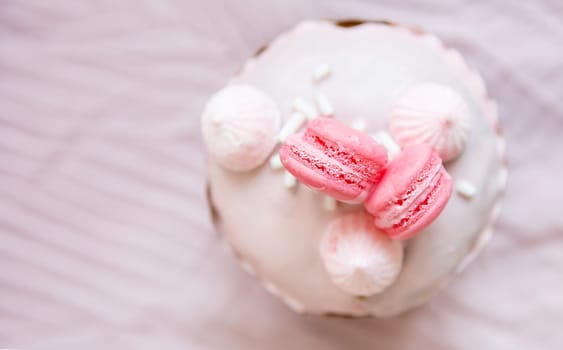 A traditional paska decorated with pink swiss chocolate and meringue stands on a pink tablecloth. Easter holiday, top view. Place for writing