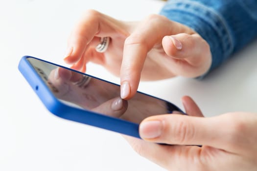 The girl is holding a smartphone in her hands. The concept of working online, freelancing, correspondence, chat. Close-up