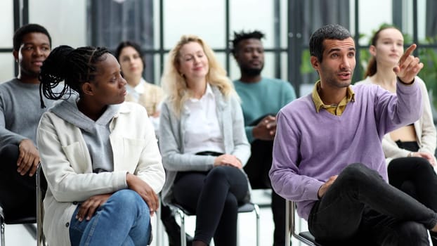 Close-up of people chatting, sitting in a circle and gesturing in a conference room