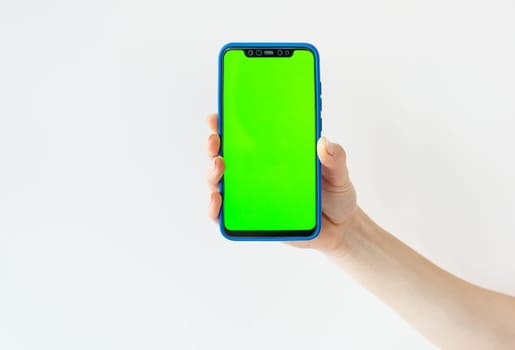 Mockup image, girl holding smartphone with blank green screen on white wall. Ready mockup for designers