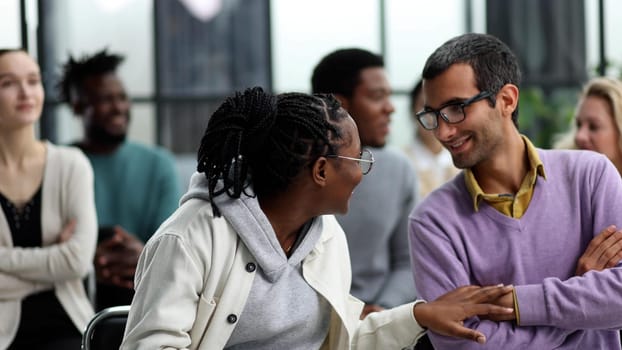 black woman communicates with a man in glasses at a seminar in a conference room
