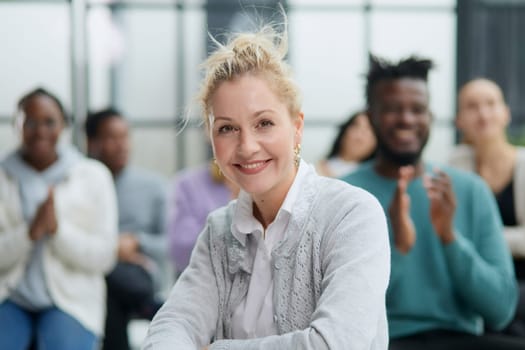 Business woman sitting on a chair with her staff in the background