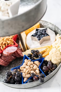 July 4th charcuterie board on a two-tiered serving metal stand filled with cheese, crackers, salami, and fresh fruits