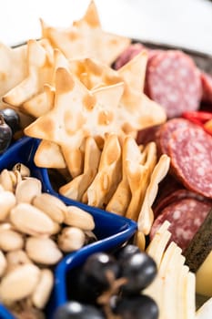 July 4th charcuterie board on a two-tiered serving metal stand filled with cheese, crackers, salami, and fresh fruits