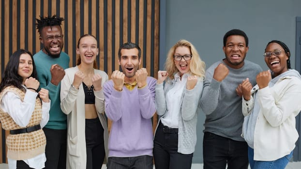 Group portrait of happy people fist pumping standing in office meeting